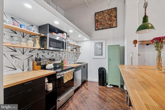 kitchen with butcher block countertops, dark cabinetry, open shelves, dark wood-type flooring, and appliances with stainless steel finishes