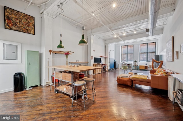 living room featuring electric panel, hardwood / wood-style floors, beam ceiling, rail lighting, and a high ceiling