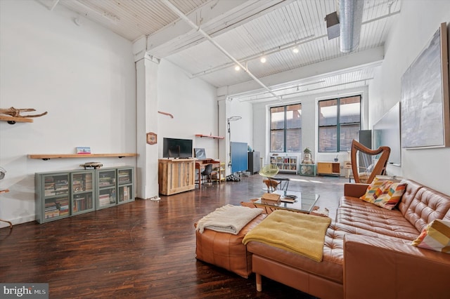 living room with beam ceiling, a high ceiling, and wood finished floors