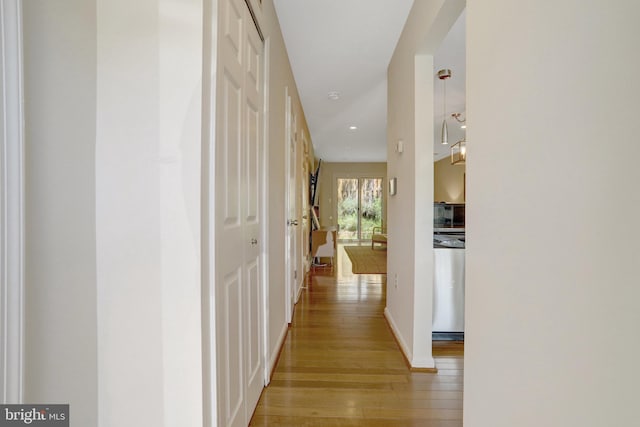 corridor with baseboards, light wood-style flooring, and recessed lighting