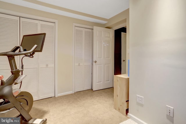 exercise room with light tile patterned flooring and baseboards