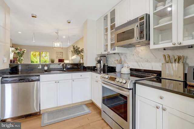 kitchen with decorative light fixtures, white cabinetry, backsplash, light wood-style floors, and stainless steel appliances