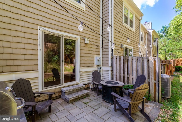 view of patio with central air condition unit, an outdoor fire pit, and fence