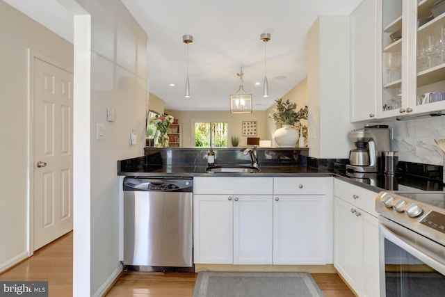 kitchen with a sink, appliances with stainless steel finishes, glass insert cabinets, white cabinets, and light wood-style floors