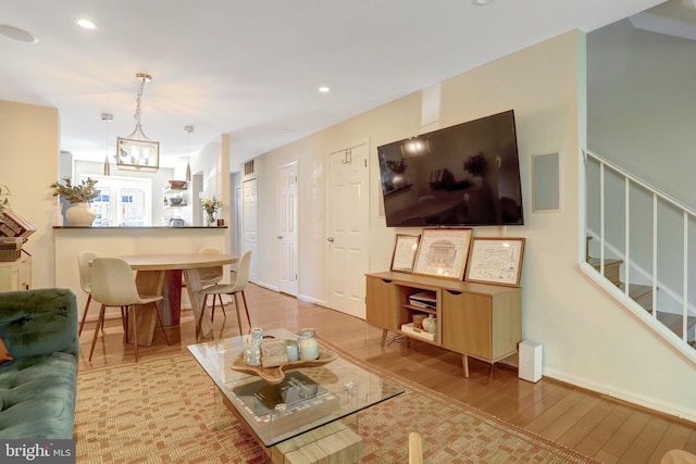 living room featuring wood finished floors, stairway, baseboards, a chandelier, and recessed lighting