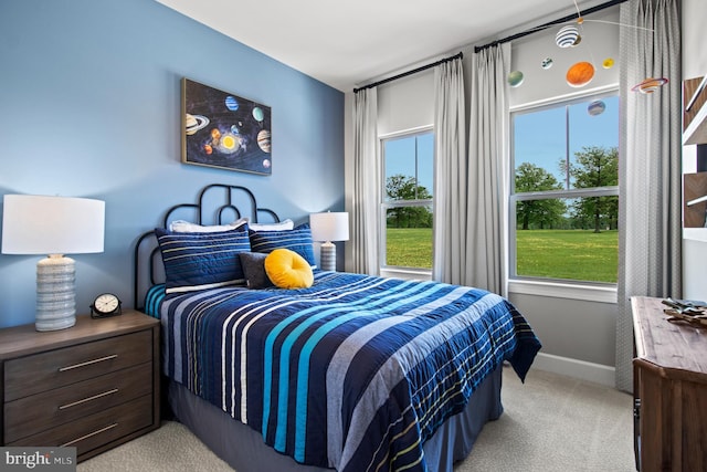 bedroom with baseboards, multiple windows, and light carpet