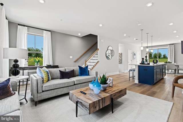 living area featuring baseboards, stairs, light wood-style floors, and recessed lighting