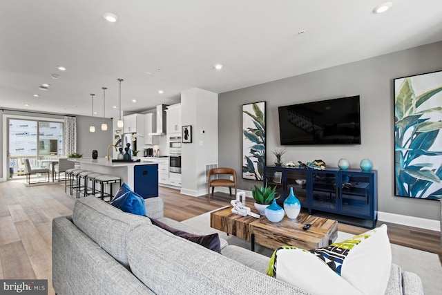 living area featuring baseboards, light wood-type flooring, and recessed lighting
