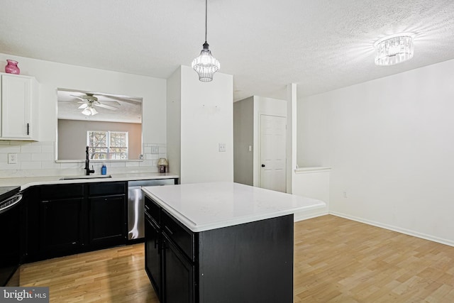 kitchen featuring a sink, light wood-type flooring, dishwasher, backsplash, and dark cabinetry