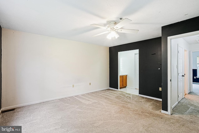 unfurnished bedroom with ensuite bathroom, light colored carpet, visible vents, ceiling fan, and baseboards
