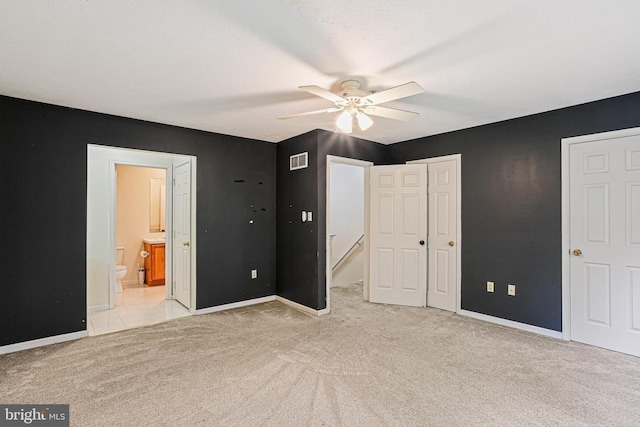 unfurnished bedroom featuring ensuite bathroom, a closet, light colored carpet, visible vents, and baseboards