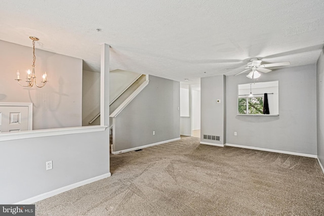 unfurnished living room with ceiling fan with notable chandelier, carpet floors, baseboards, and visible vents