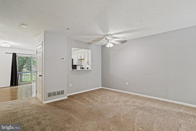 unfurnished room featuring carpet flooring, a ceiling fan, a textured ceiling, visible vents, and baseboards