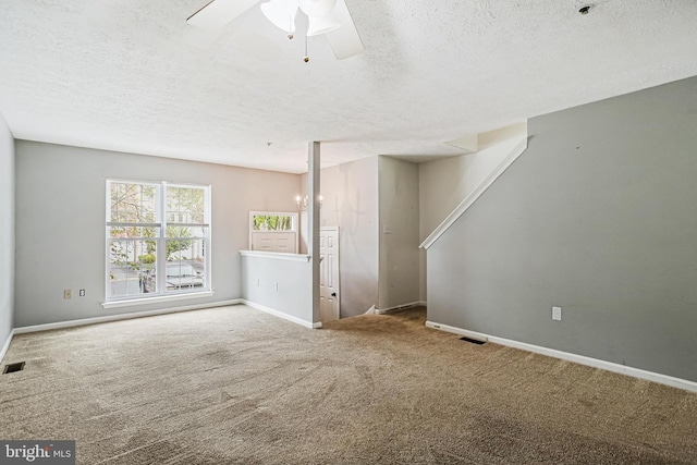 unfurnished living room featuring a textured ceiling, carpet, baseboards, and a ceiling fan