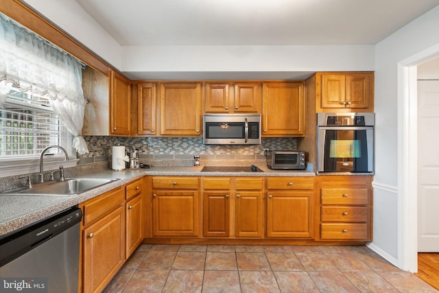 kitchen with stainless steel appliances, a sink, tasteful backsplash, and brown cabinetry