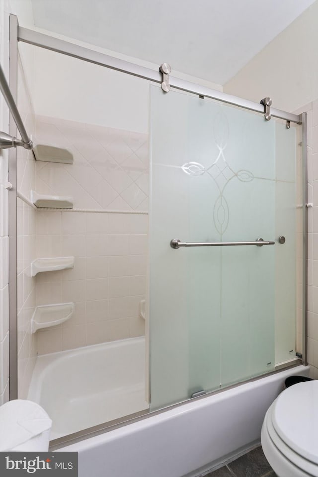 bathroom with toilet and bath / shower combo with glass door