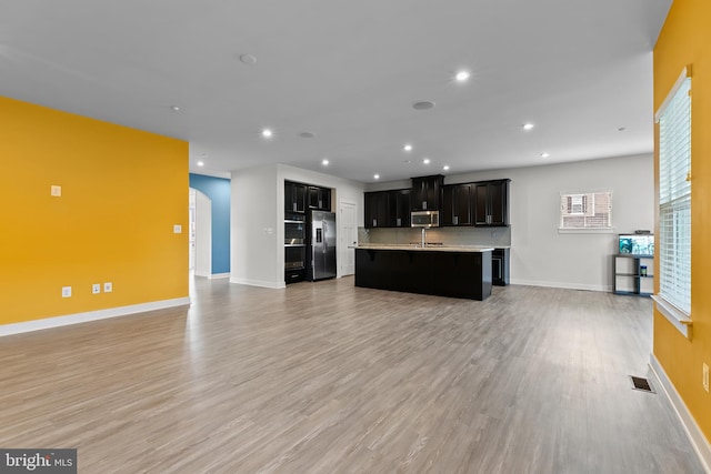 kitchen featuring stainless steel appliances, open floor plan, dark cabinets, baseboards, and recessed lighting