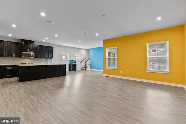 kitchen featuring appliances with stainless steel finishes, open floor plan, recessed lighting, light countertops, and a breakfast bar