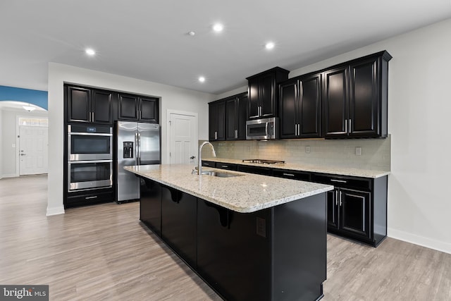 kitchen with stainless steel appliances, dark cabinetry, a sink, baseboards, and recessed lighting