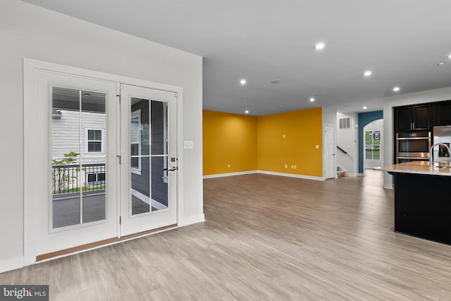 kitchen featuring light wood-style floors, baseboards, light stone countertops, dark cabinetry, and recessed lighting