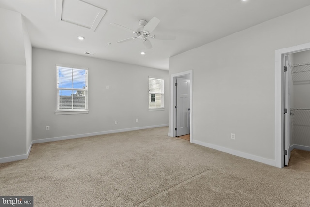 unfurnished bedroom with a walk in closet, light colored carpet, multiple windows, and recessed lighting