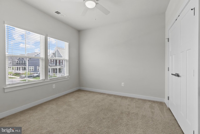 spare room featuring light colored carpet, baseboards, and a ceiling fan