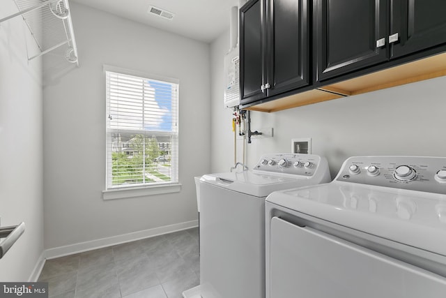 clothes washing area featuring separate washer and dryer, cabinet space, baseboards, and light tile patterned floors