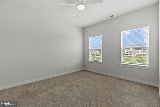empty room featuring plenty of natural light, carpet flooring, baseboards, and ceiling fan