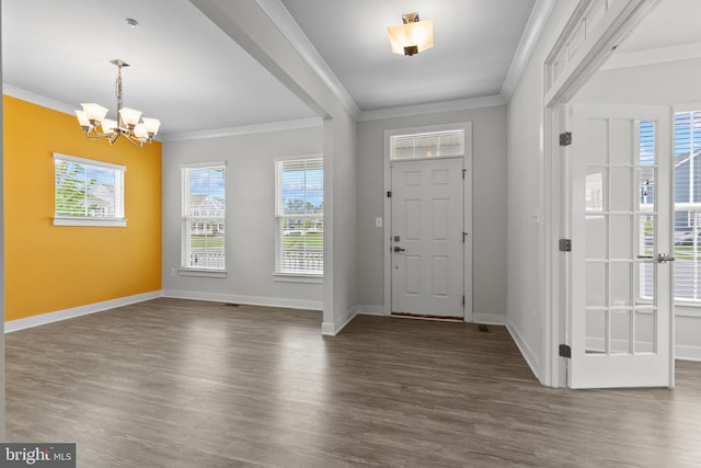 entryway featuring dark wood-type flooring, a chandelier, ornamental molding, plenty of natural light, and baseboards