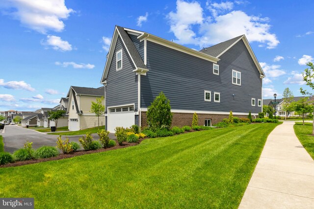 view of side of home with an attached garage, a yard, asphalt driveway, and a residential view