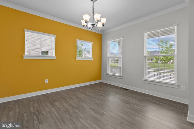 spare room with crown molding, a chandelier, dark wood finished floors, and baseboards