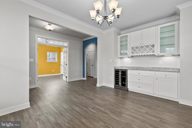 kitchen with wine cooler, arched walkways, dark wood-style floors, baseboards, and crown molding