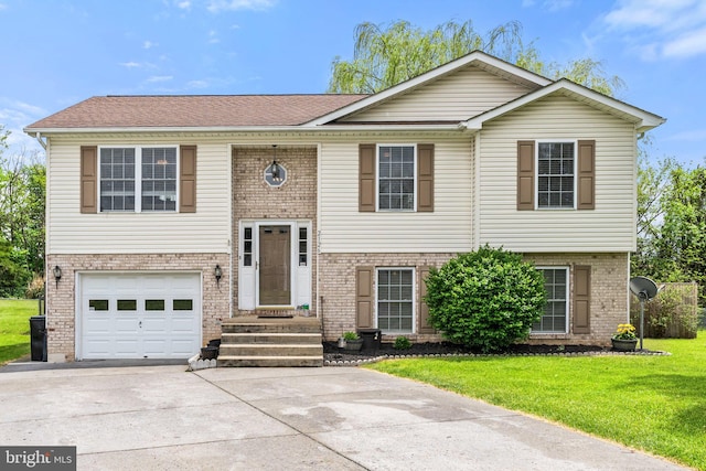 split foyer home featuring an attached garage, brick siding, concrete driveway, entry steps, and a front lawn
