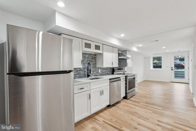 660 Columbia Rd NW, Washington, DC 20001 - kitchen featuring stainless steel appliances, wall chimney range hood, a sink, light countertops, and light wood-type flooring