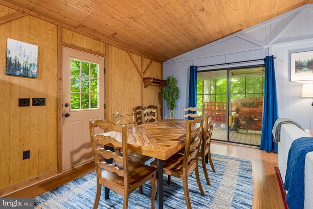 dining room with vaulted ceiling, wood finished floors, wooden walls, and wooden ceiling
