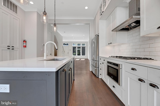 kitchen featuring a sink, stainless steel appliances, visible vents, wall chimney range hood, and dark wood-style floors