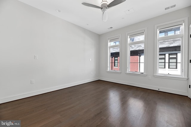 empty room featuring baseboards, dark wood finished floors, visible vents, and a ceiling fan