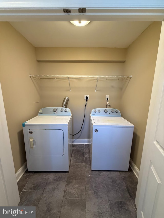 clothes washing area with independent washer and dryer and baseboards