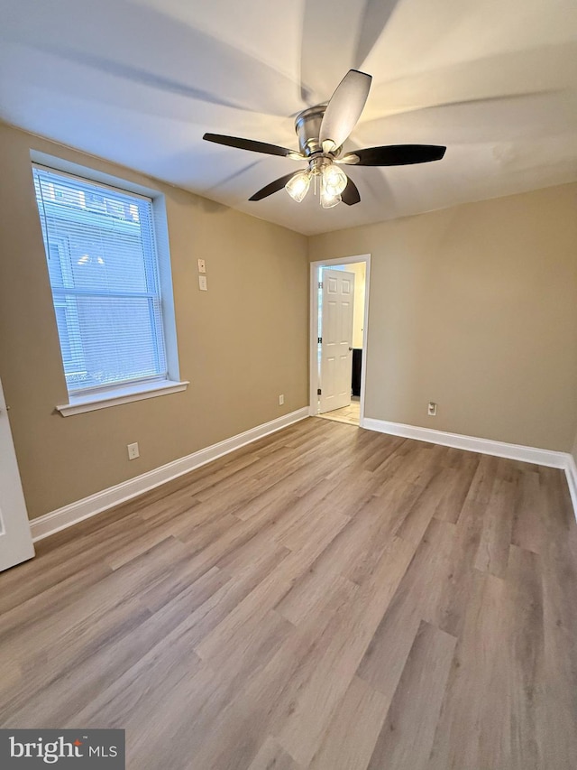 empty room featuring wood finished floors, baseboards, and a ceiling fan