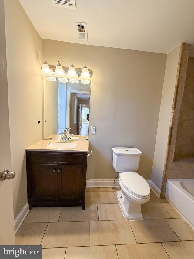 bathroom featuring tile patterned flooring, a tub to relax in, toilet, vanity, and baseboards
