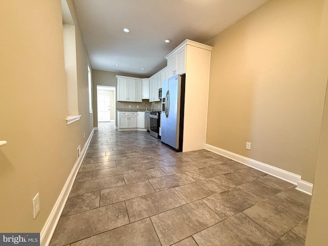 kitchen with stainless steel appliances, baseboards, white cabinetry, a sink, and recessed lighting