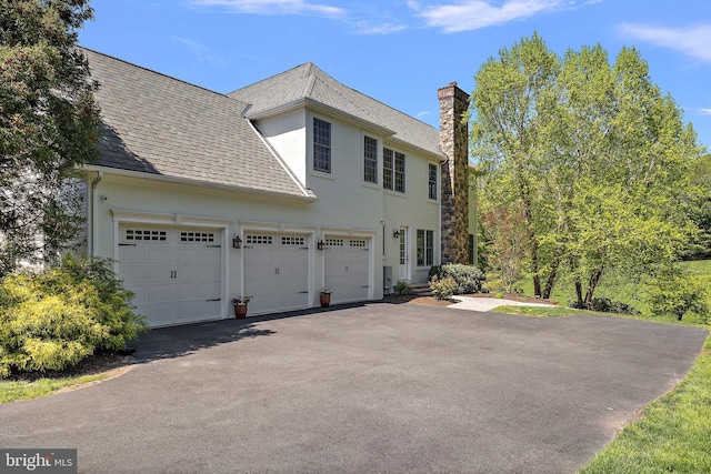 107 Centrenest Ln, Wilmington, DE 19807 - view of side of property with an attached garage, a high end roof, driveway, stucco siding, and a chimney