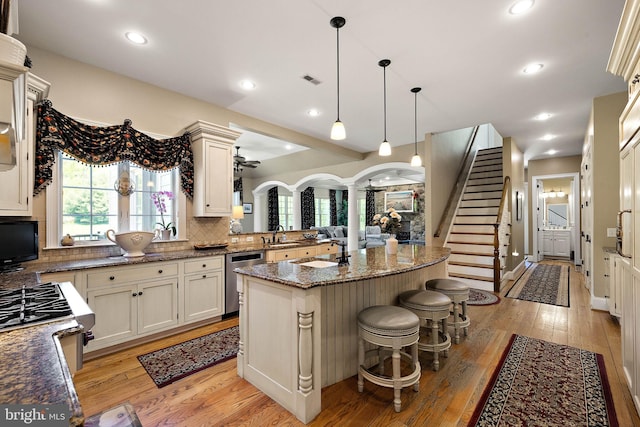 107 Centrenest Ln, Wilmington, DE 19807 - kitchen featuring ornate columns, dark stone counters, light wood-type flooring, dishwasher, and tasteful backsplash