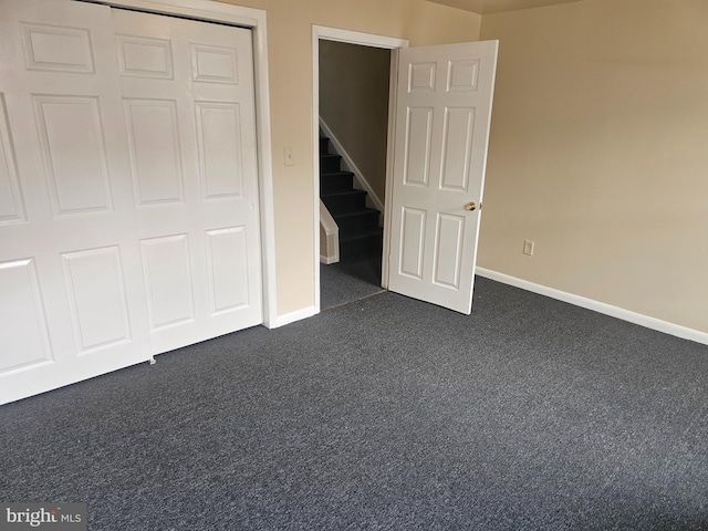 unfurnished bedroom with dark colored carpet and baseboards