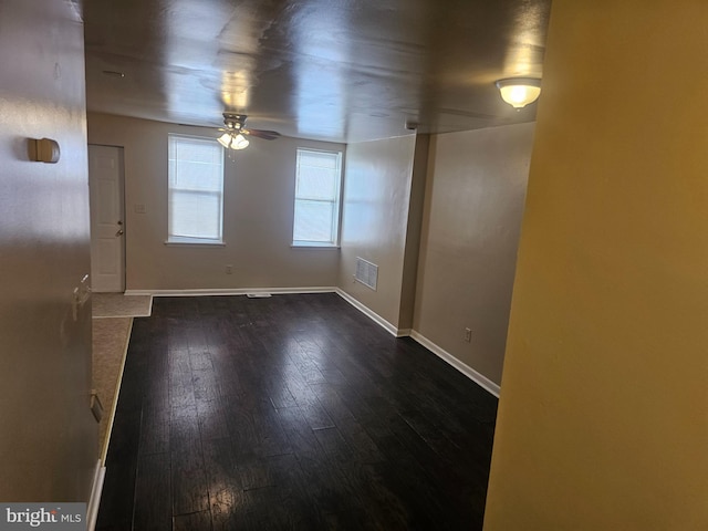 unfurnished room featuring a ceiling fan, dark wood-style floors, and baseboards