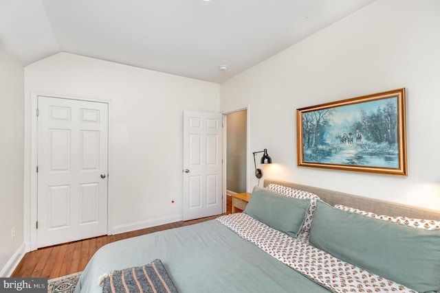 bedroom with lofted ceiling, baseboards, and wood finished floors