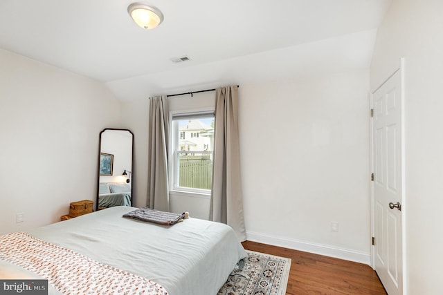bedroom featuring vaulted ceiling, visible vents, wood finished floors, and baseboards