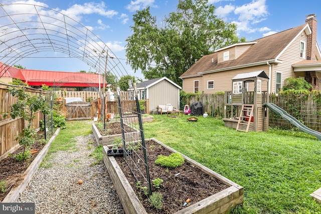 view of yard with a fenced backyard, a garden, and a playground