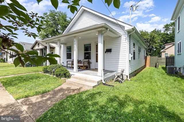 view of front of home featuring central air condition unit, a front yard, covered porch, and fence