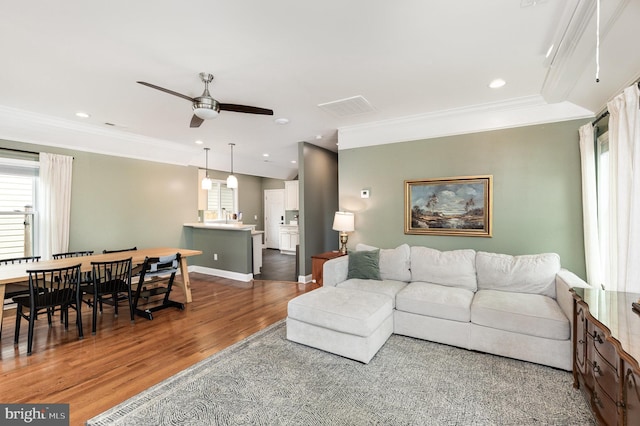 living room with crown molding, visible vents, wood finished floors, and ceiling fan